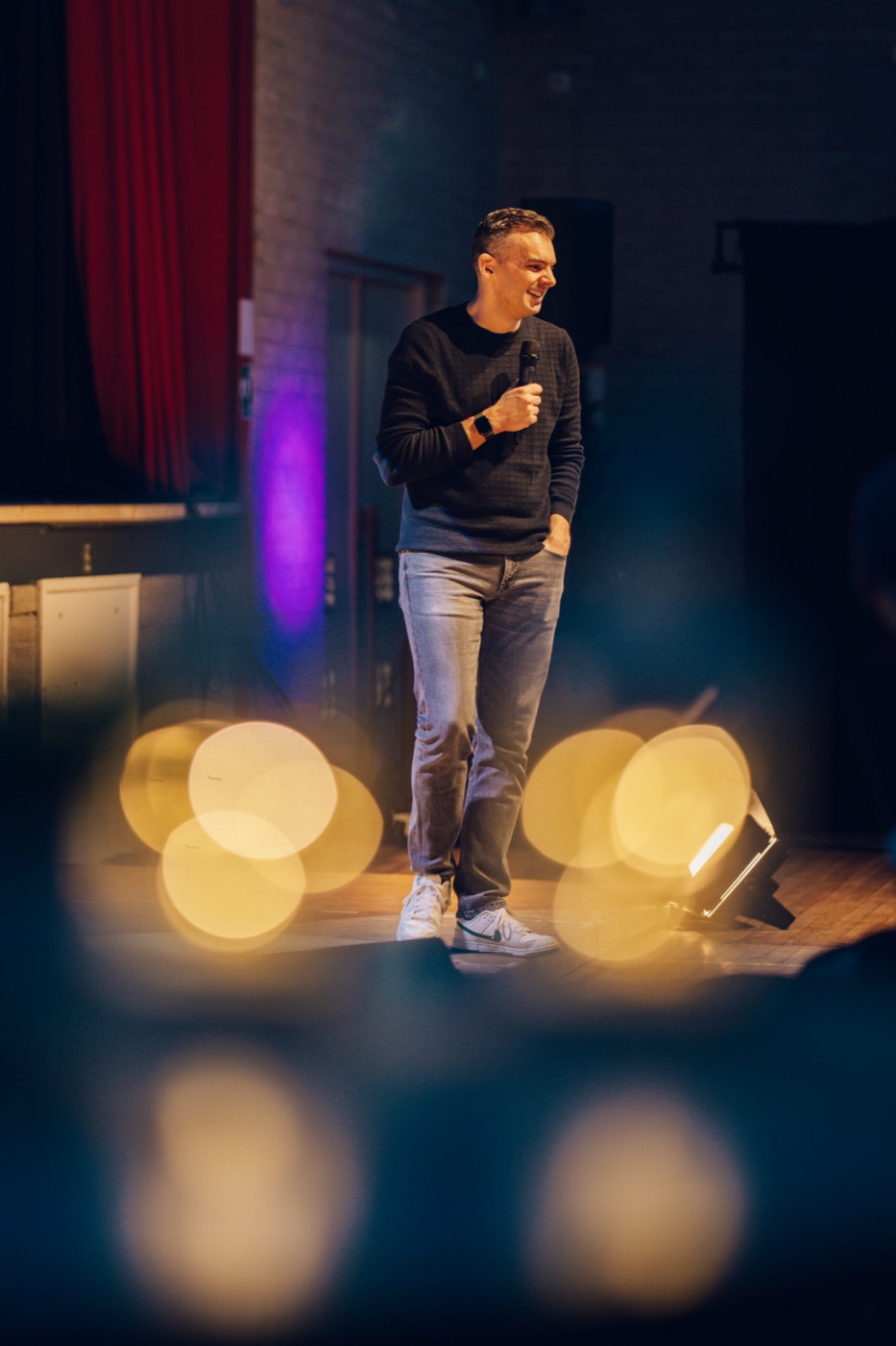 Spreker op het podium met warme lichtjes op de voorgrond